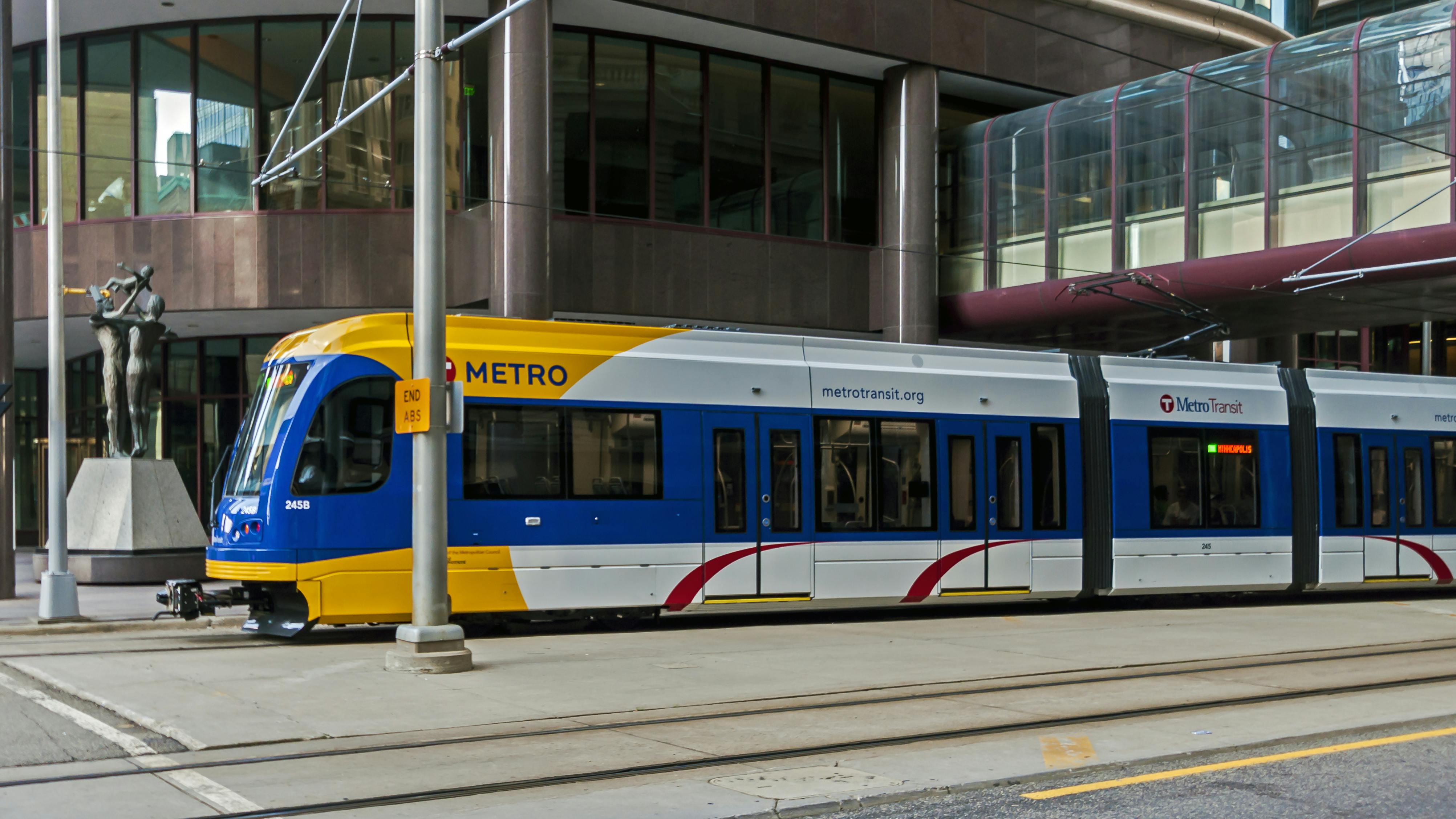 The image shows a Metro Transit light-rail train roll down the track.