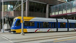 The image shows a Metro Transit light-rail train roll down the track. The image shows a Metro Transit light-rail train roll down the track.