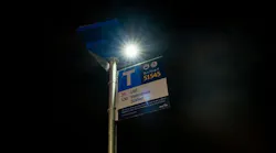 A solar light is shown mounted atop a bus stop pole.
