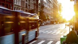 New York City bus driving through the intersection of 23rd Street and 5th Avenue in Manhattan with the light of sunset shining. New York City bus driving through the intersection of 23rd Street and 5th Avenue in Manhattan with the light of sunset shining.