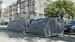 Bike storage sheds are spread out in front of parking spaces. Bike storage sheds are spread out in front of parking spaces.