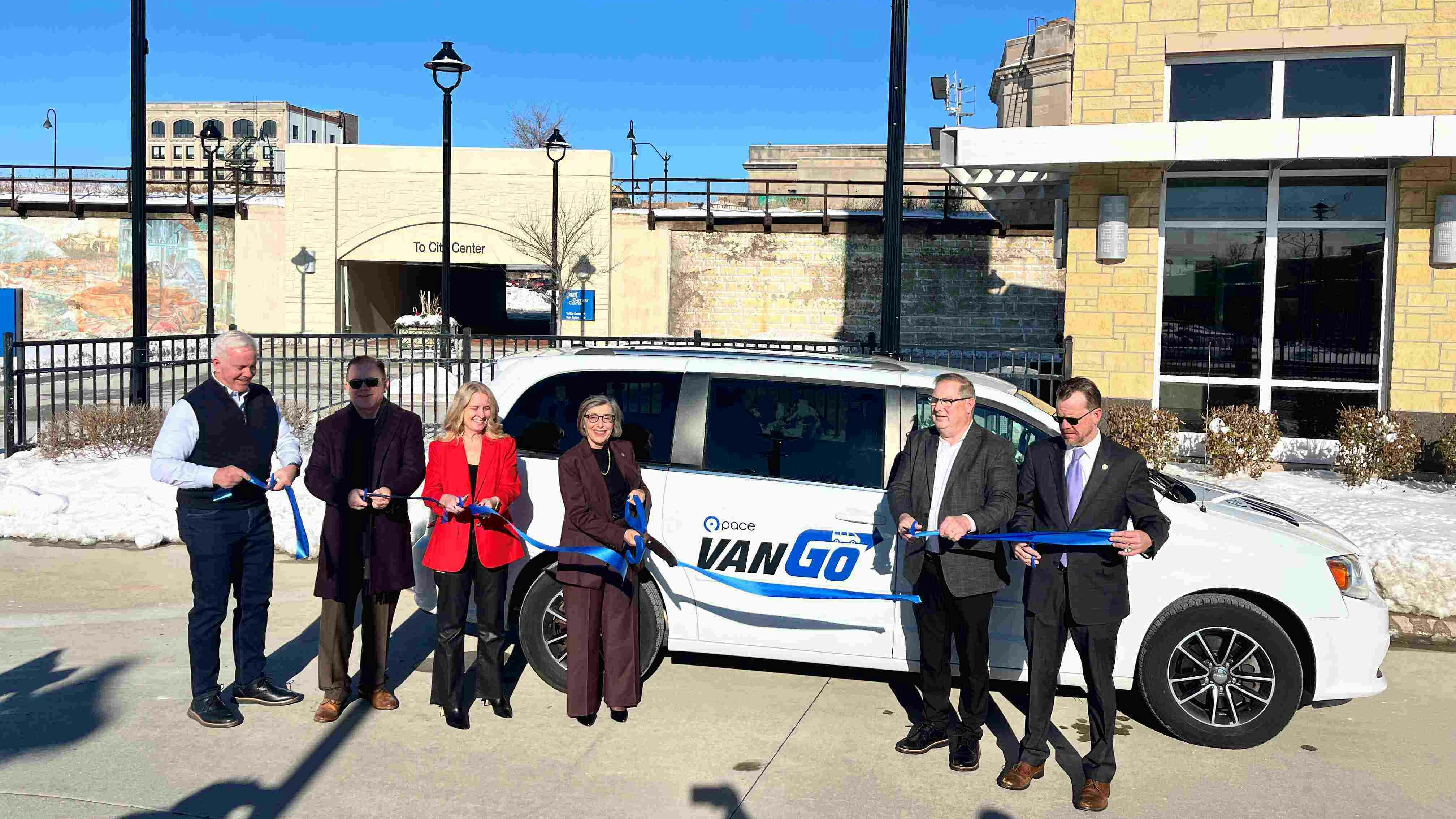 Local leaders gathered to cut a ribbon in front of a new VanGo van.