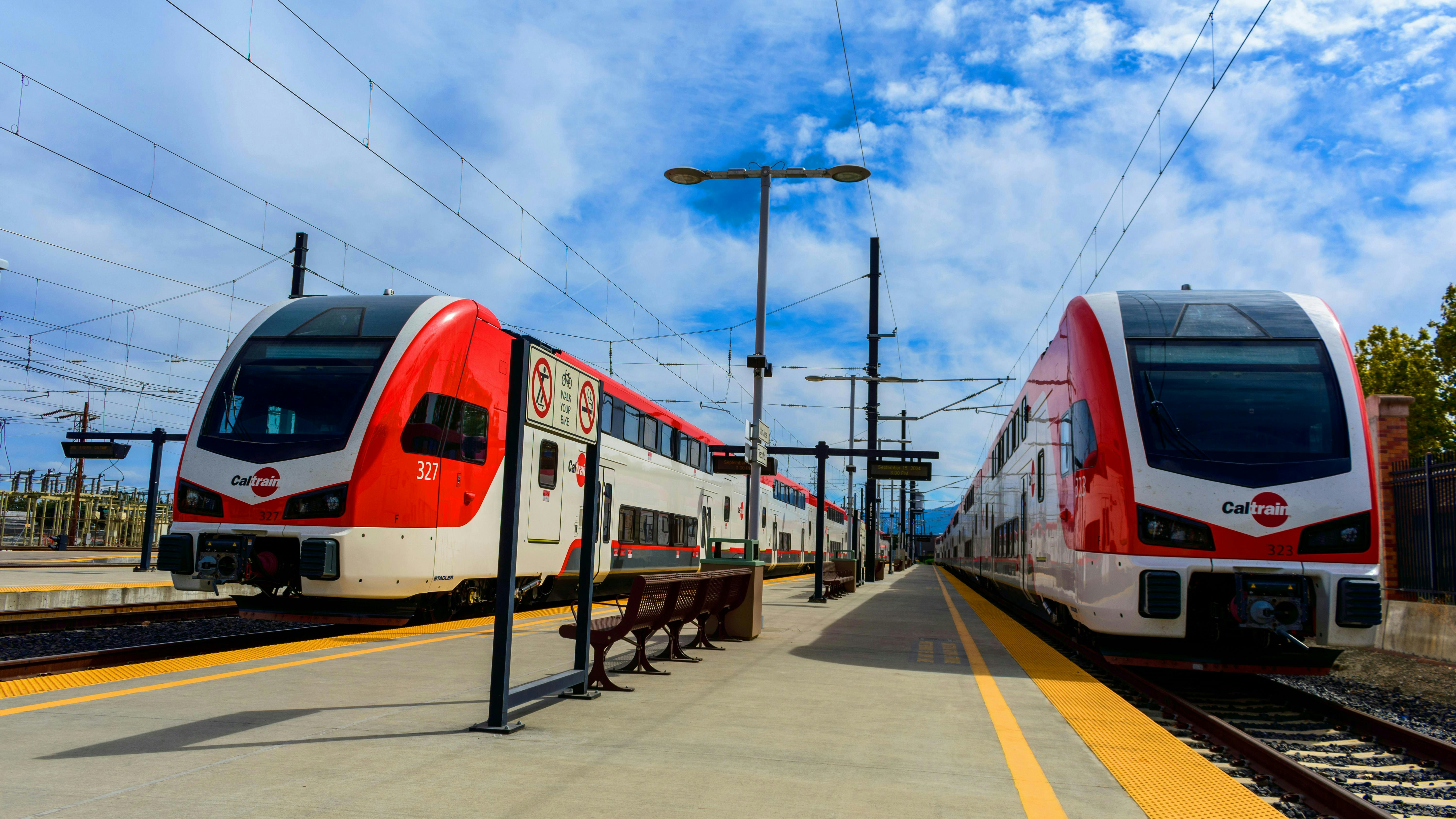 A pair of electric Caltrain trains sit at a station.