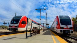 A pair of electric Caltrain trains sit at a station. A pair of electric Caltrain trains sit at a station.