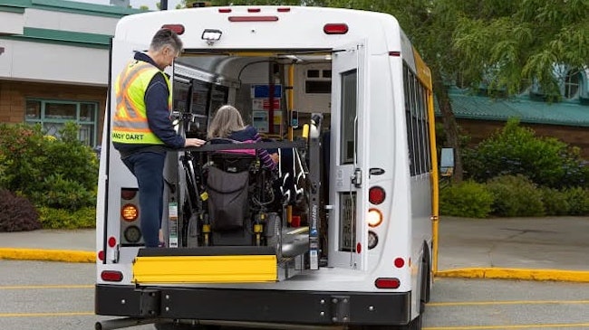 A HandyDART operator assists a rider entering into a vehicles.