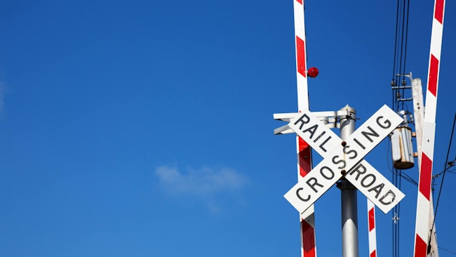 Railroad crossing sign against blue sky background.