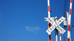 Railroad crossing sign against blue sky background.