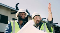 Construction workers talk over plans and point at a construction site. Construction workers talk over plans and point at a construction site.