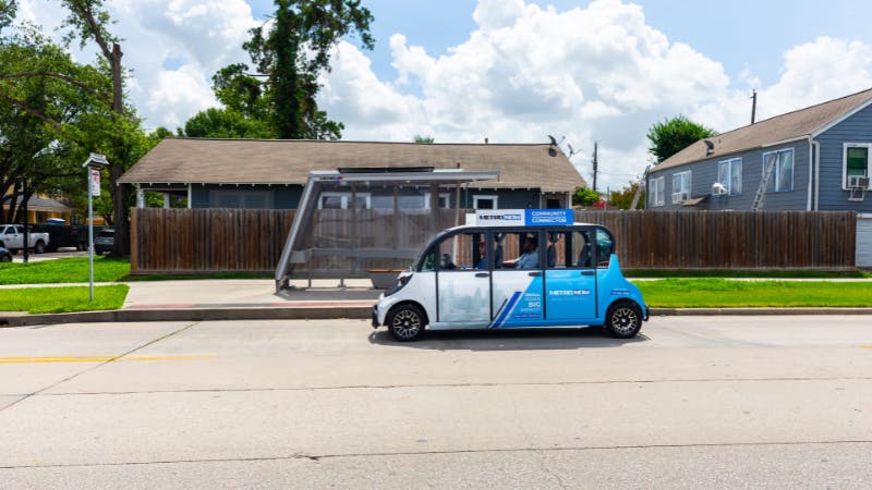 A microtransit vehicle sits parked in front of a stop.