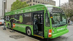 The image shows an electric Nova Bus parked at a bus stop. The image shows an electric Nova Bus parked at a bus stop.