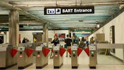 Entrance fare gates to Powell Street BART Station with people in station Entrance fare gates to Powell Street BART Station with people in station