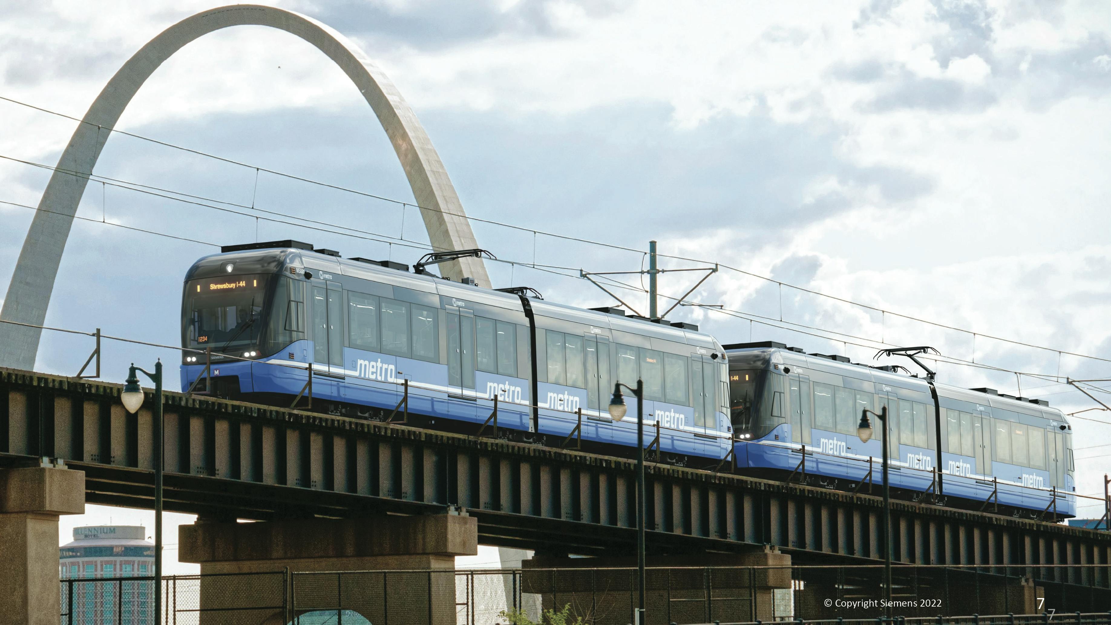 The image displays a rendering of the future LRVs on a track in front of the Arch.