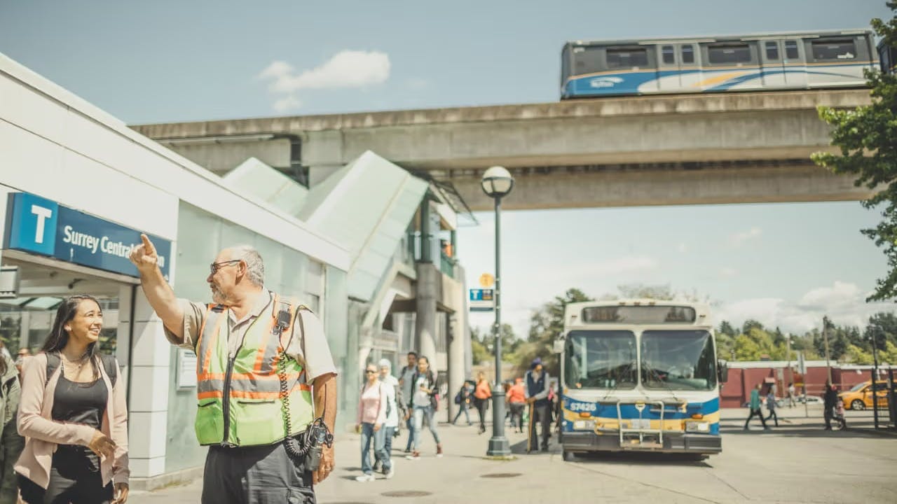 A TransLink employee aids a customer with directions outside of a transit center.