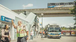 A TransLink employee aids a customer with directions outside of a transit center.