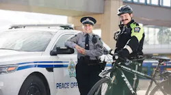 Transit peace officers stand posed in front of a patrol car and bike.