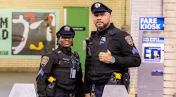 Two SEPTA officers stand in front of fare gates.
