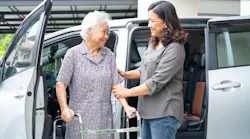 A SilverRide operator aids a passenger exiting a van. A SilverRide operator aids a passenger exiting a van.