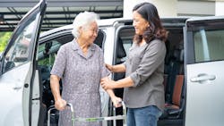 A SilverRide operator aids a passenger exiting a van. A SilverRide operator aids a passenger exiting a van.