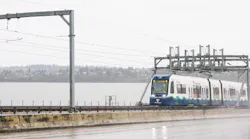A Sound Transit light-rail vehicle crosses water on a floating bridge.