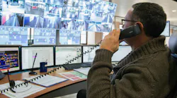 man on telephone in front of computer safety monitors in control room