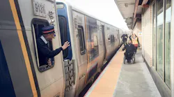 A conductor waves at a passenger in a wheelchair approaching the train at the newly upgraded Laurelton Station.