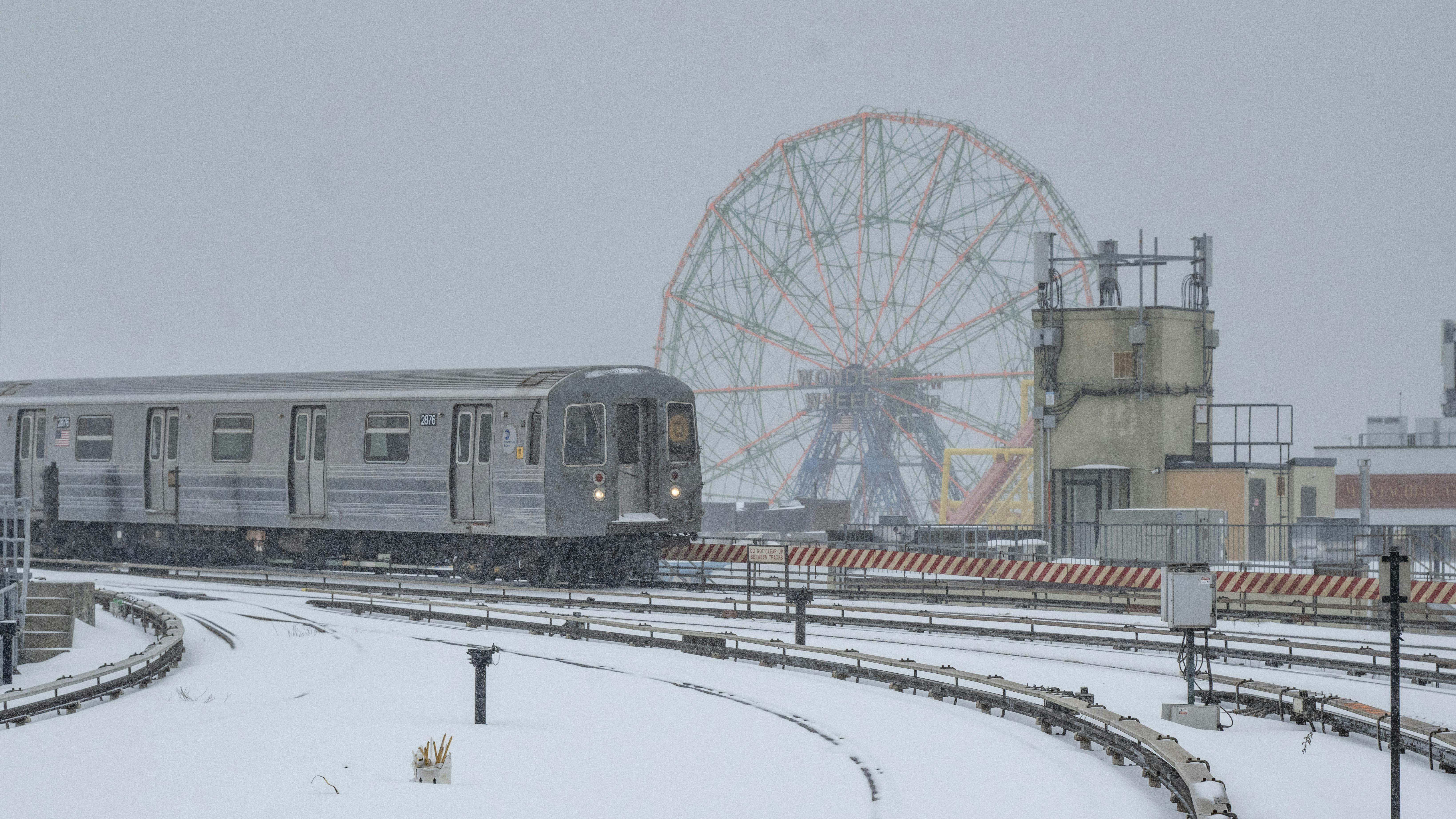 A Q train moves down the tracks during a snowstorm.