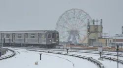 A Q train moves down the tracks during a snowstorm.