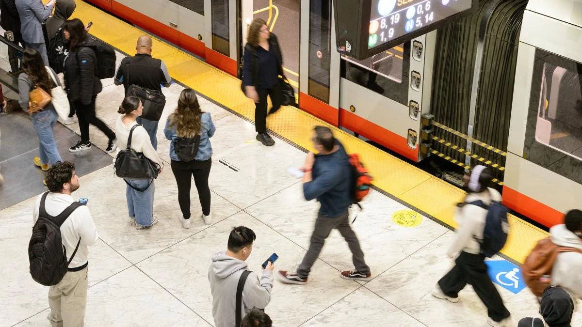 Riders use cell phones on the platform as they wait for a train.