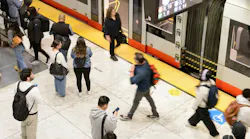 Riders use cell phones on the platform as they wait for a train.