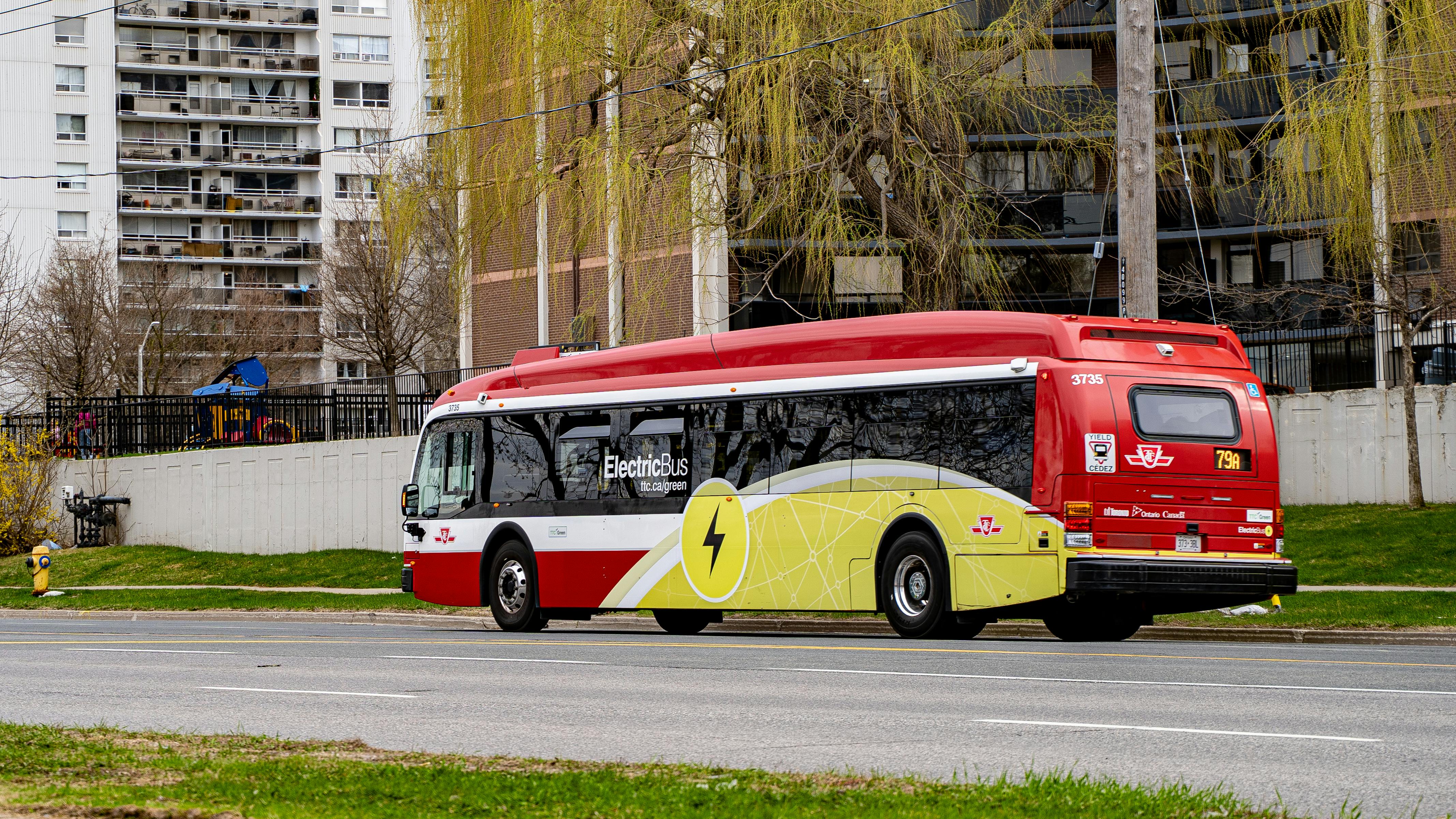 An electric TTC bus drives down an empty street.