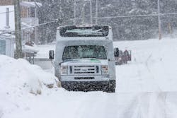 An on-demand transit vehicle drives through the snow. An on-demand transit vehicle drives through the snow.