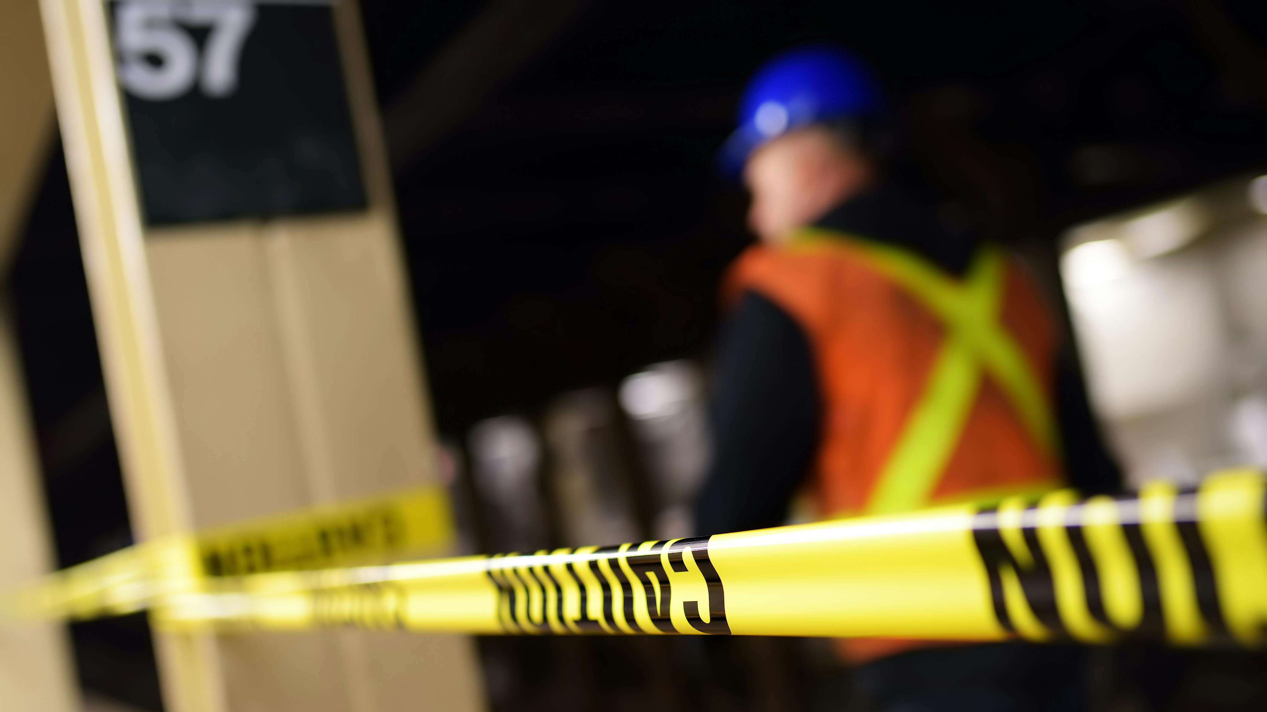 The image shows a blurred construction worker conducting work in the 57th Street station.
