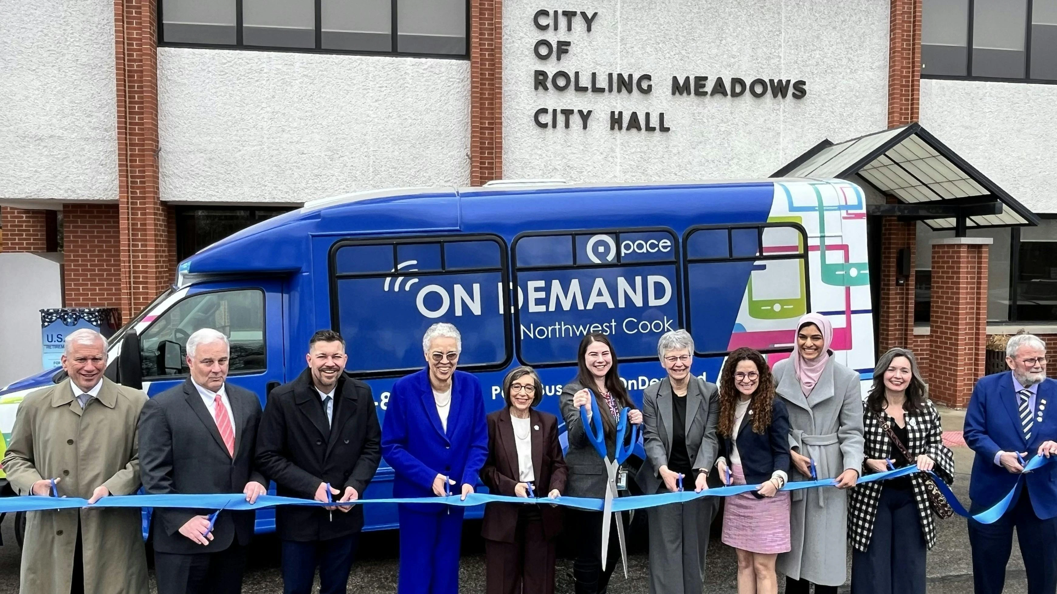 Cook County leaders start in front of a new On Demand vehicles snipping a blue ribbon.