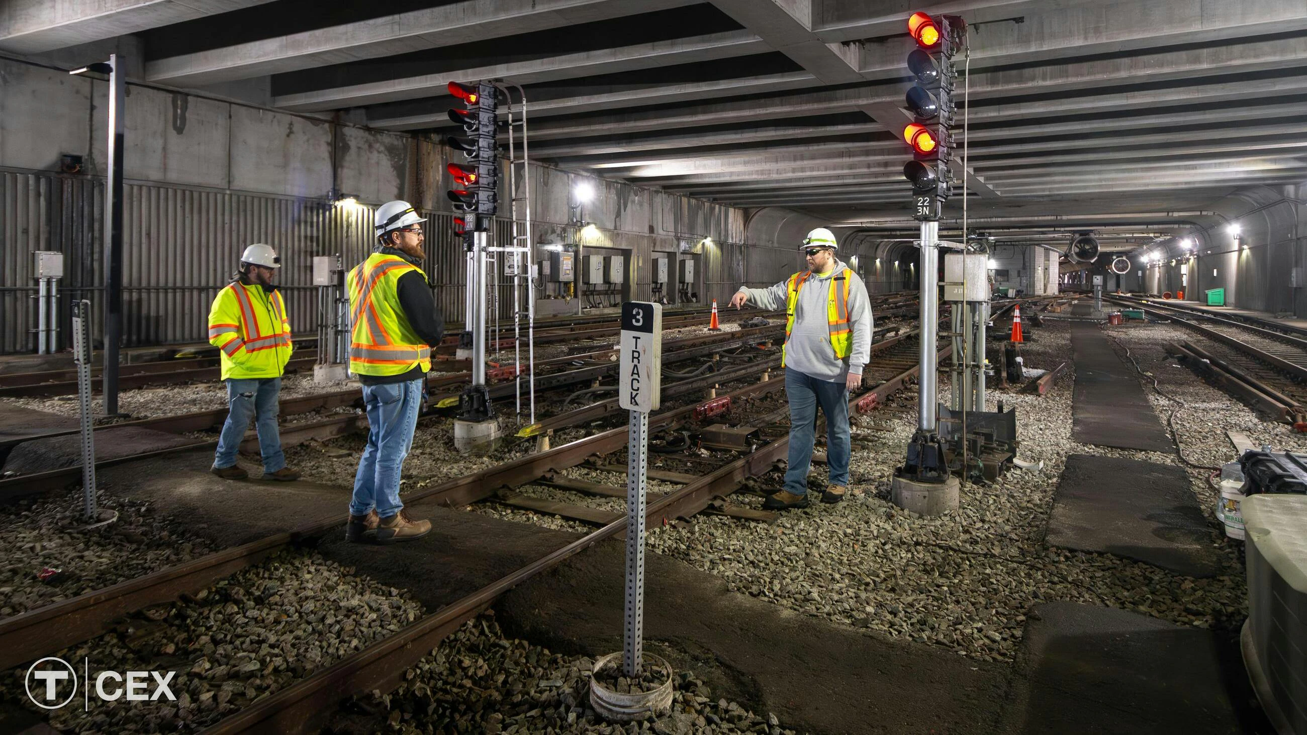 =An MBTA construction crew discusses work in a tunnel near signaling equipment.