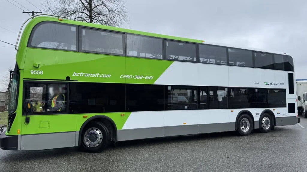 The image shows the side profile of one of the new double decker buses wrapped in green livery.
