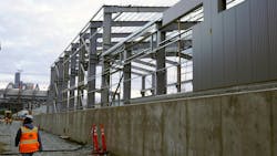 A construction worker walks alongside the new structure. A construction worker walks alongside the new structure.