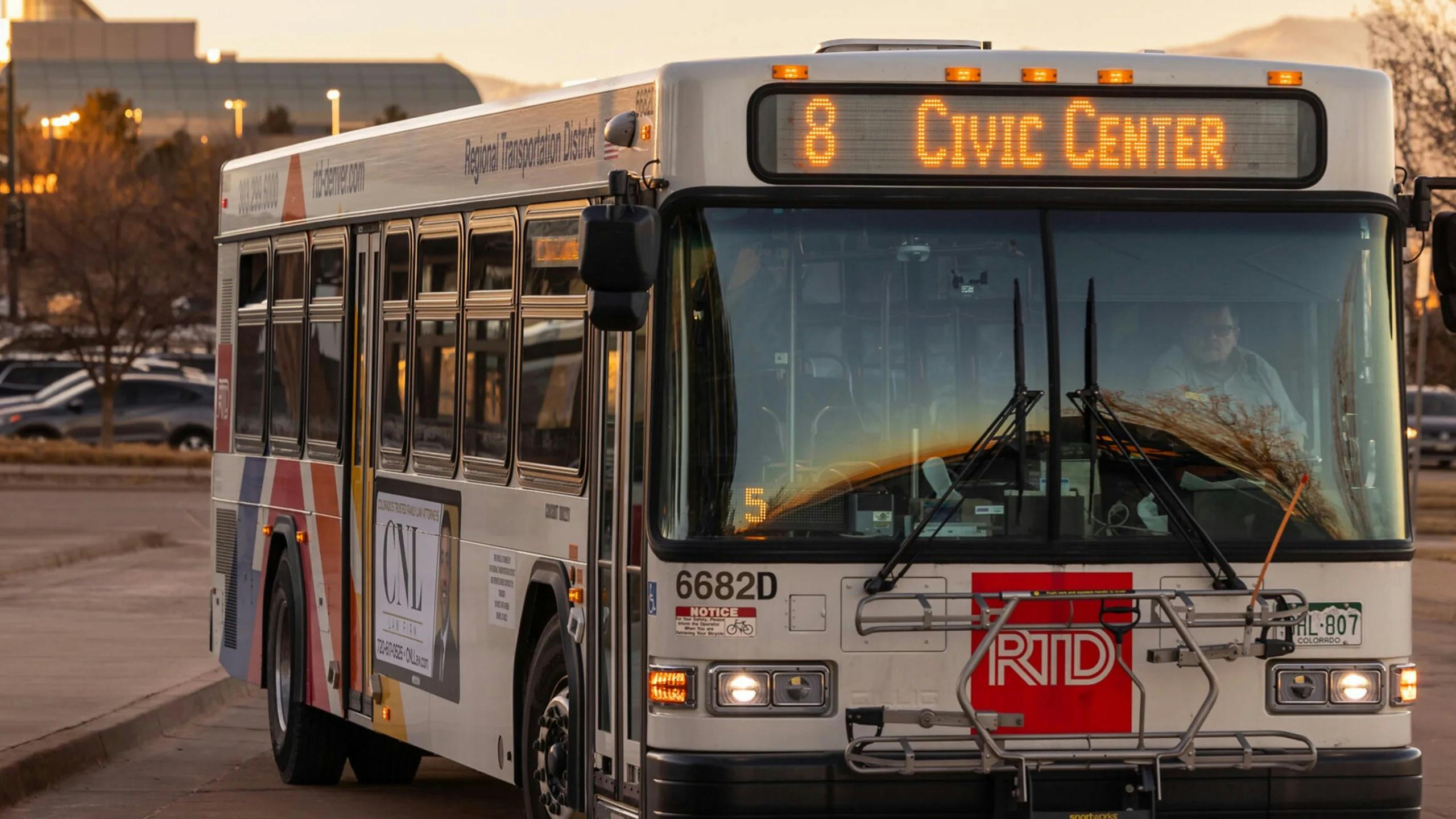 A Denver RTD bus drives down the street in the evening.