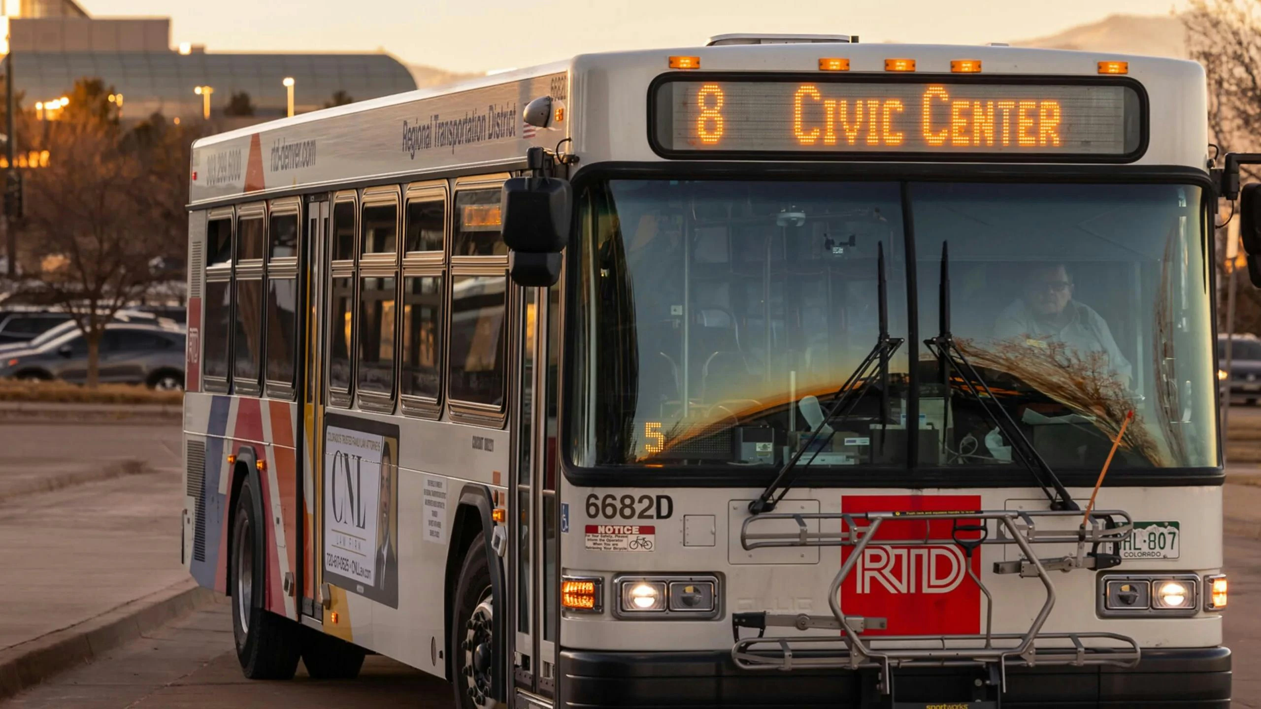 A Denver RTD bus drives down the street in the evening.