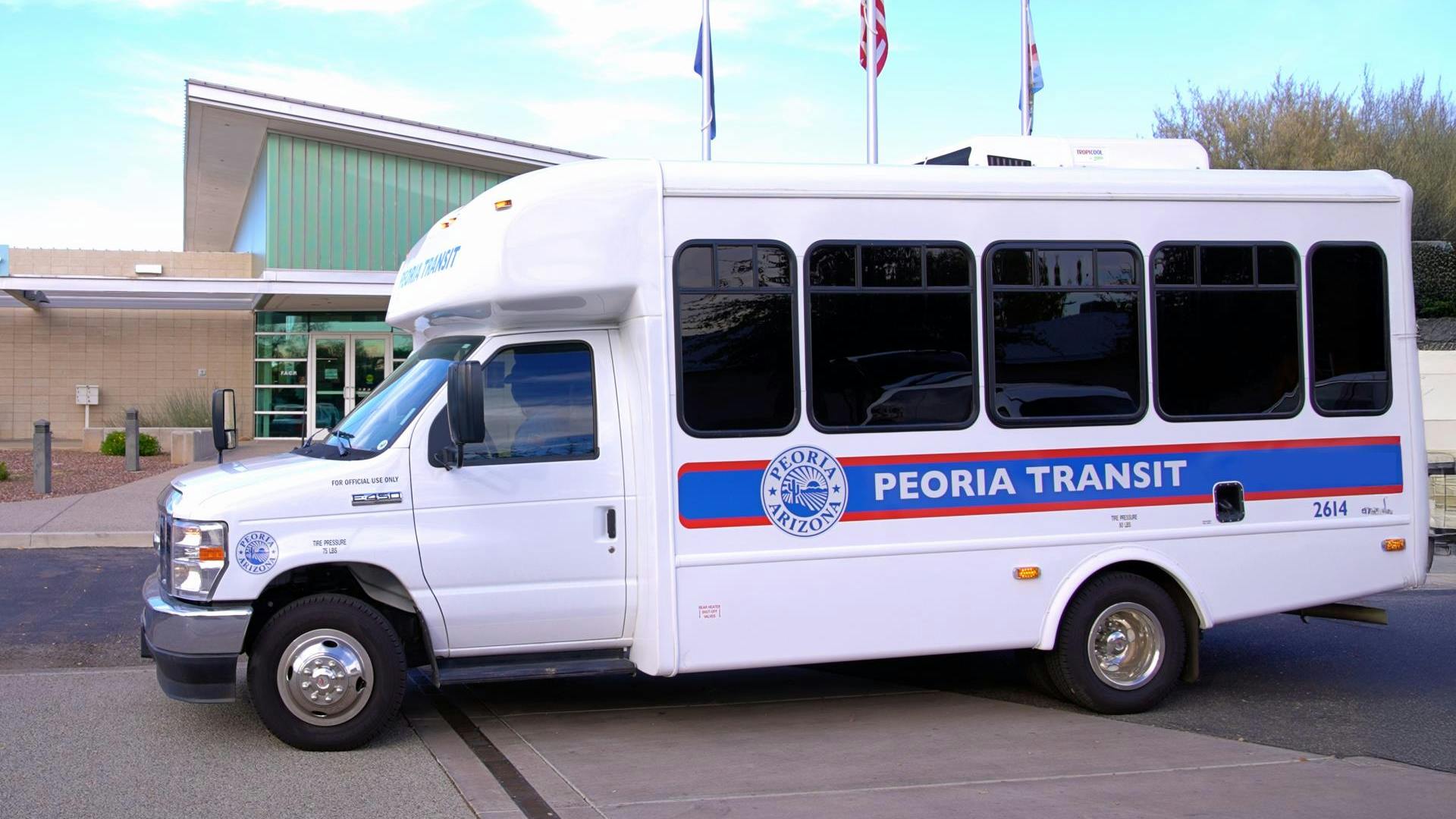 A new Peoria Transit bus sits parked in front of a building.