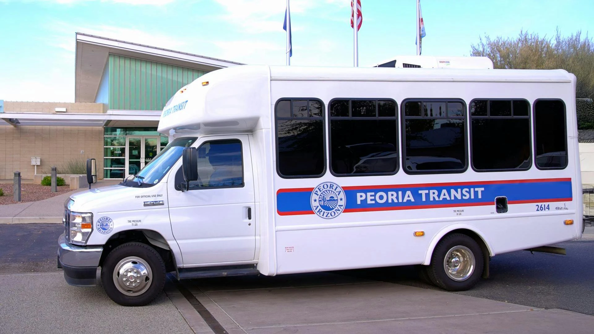 A new Peoria Transit bus sits parked in front of a building.