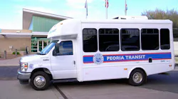 A new Peoria Transit bus sits parked in front of a building.