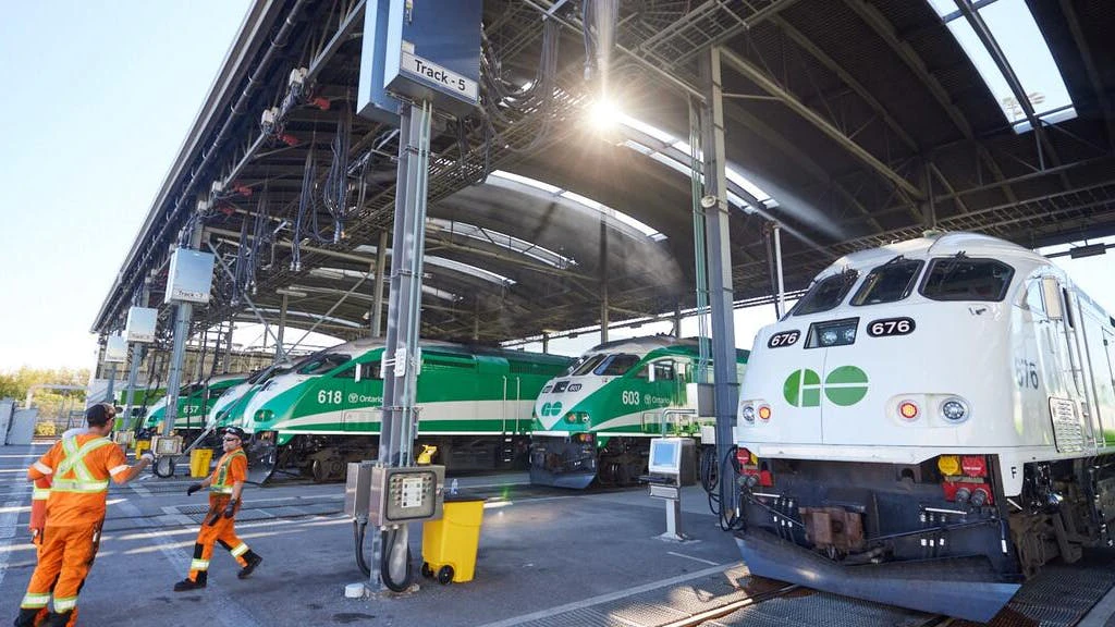 Workers in high-vis gear speak outside of GO Express trains.