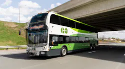 A GO Transit double-decker bus travels along a highway beneath an overpass. The destination sign reads 'Welcome to GO Transit.' The bus features the agency's white and green livery with the GO logo on its upper front panel.