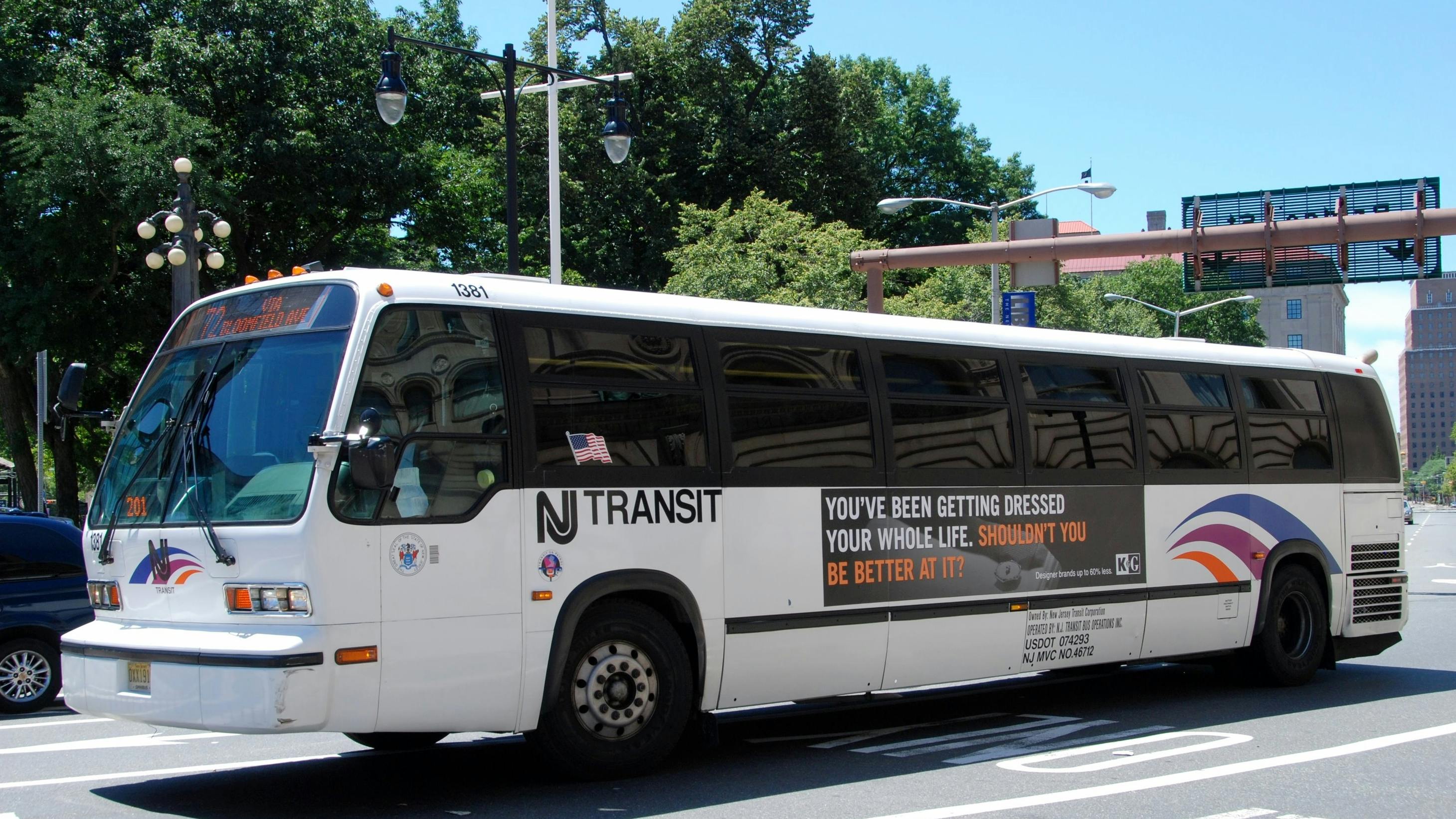 A New Jersey Transit bus with advertising on its side driving along Washington Street.