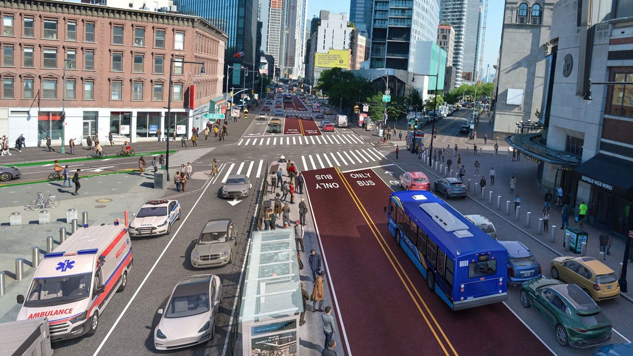 A rendering of a proposed redesign of Flatbush Avenue in Brooklyn, New York, viewed from an elevated angle looking north toward the Manhattan Bridge area. Two dedicated bus-only lanes, marked with dark red pavement and 'BUS ONLY' pavement markings in white, run along the center of the corridor. A blue New York City Transit bus travels in one of the lanes. General traffic lanes flank the bus lanes on both sides, with a police cruiser, ambulance, and several personal vehicles visible. Pedestrians fill the sidewalks and a crosswalk in the foreground. A glass subway entrance structure sits at the median. High-rise buildings and commercial storefronts line both sides of the street under a clear blue sky.
