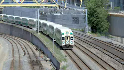 A GO Transit bi-level commuter rail train approaches on a curved, multi-track corridor in downtown Toronto, with the Concord CityPlace development visible in the background. A yellow signal gantry spans the tracks overhead, and several additional parallel tracks are visible in the foreground. A GO Transit bi-level commuter rail train approaches on a curved, multi-track corridor in downtown Toronto, with the Concord CityPlace development visible in the background. A yellow signal gantry spans the tracks overhead, and several additional parallel tracks are visible in the foreground.