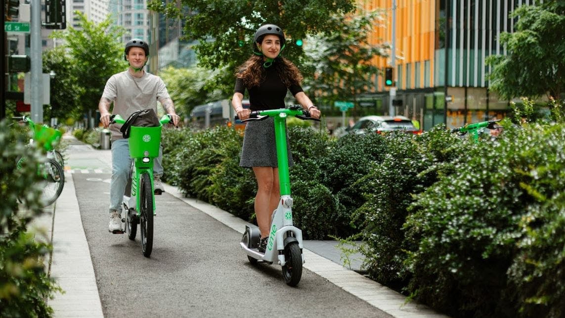 People riding a bike and scooter in a protected bike lane in Downtown Seattle.