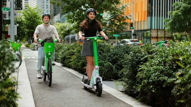 People riding a bike and scooter in a protected bike lane in Downtown Seattle.