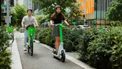 People riding a bike and scooter in a protected bike lane in Downtown Seattle. People riding a bike and scooter in a protected bike lane in Downtown Seattle.