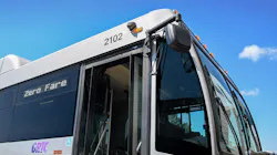 The front corner of a GRTC bus, fleet number 2102, photographed from a low angle against a bright blue sky with scattered clouds. The destination sign reads 'Zero Fare' and the front doors are open. The GRTC logo is visible in purple on the side panel near the accessibility symbol. The front corner of a GRTC bus, fleet number 2102, photographed from a low angle against a bright blue sky with scattered clouds. The destination sign reads 'Zero Fare' and the front doors are open. The GRTC logo is visible in purple on the side panel near the accessibility symbol.